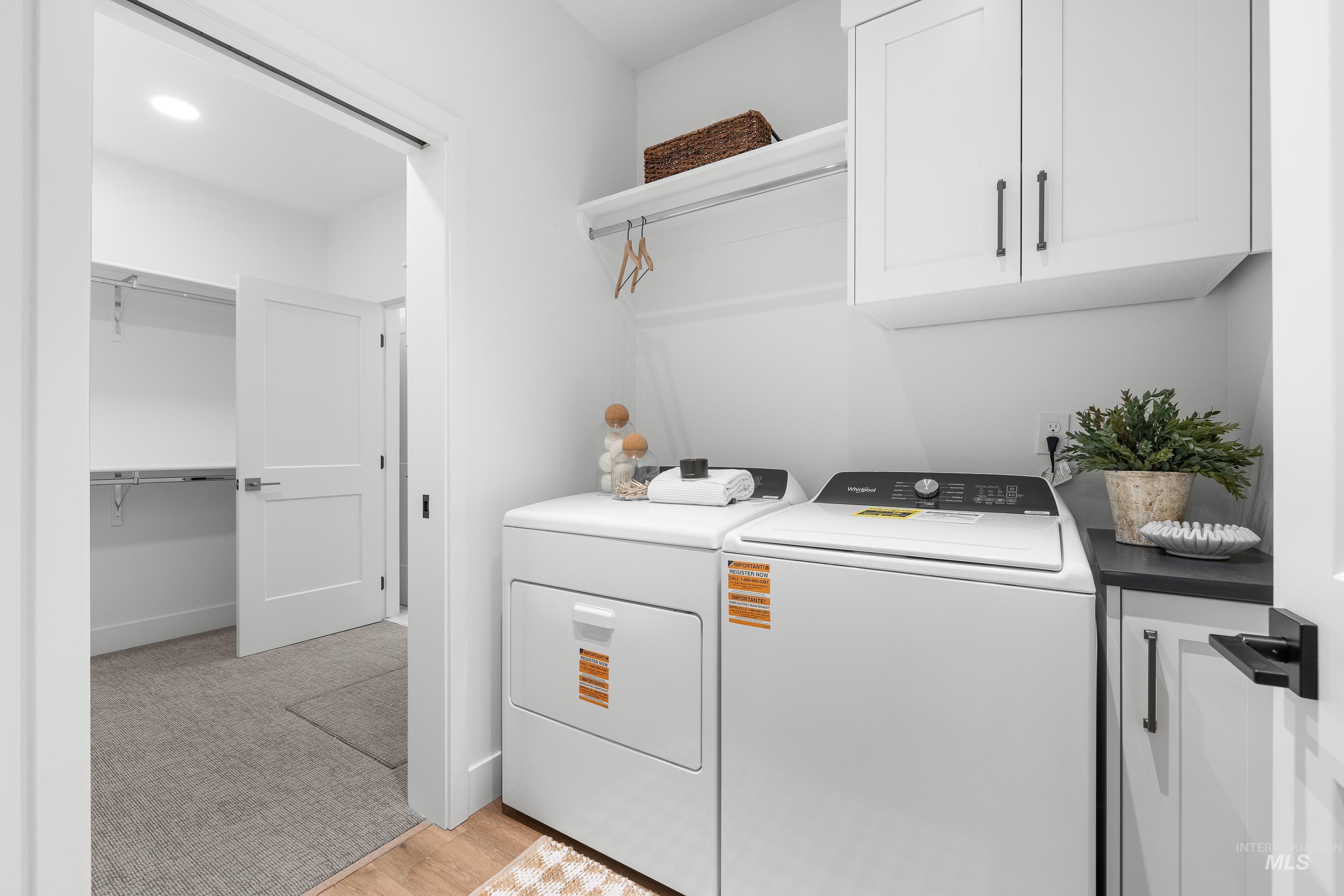 3071 North Lapis Avenue Meridian, ID 83646 - Photo 39 of 50 Laundry room with cabinet space, washing machine and dryer, light carpet, and light wood finished floors
