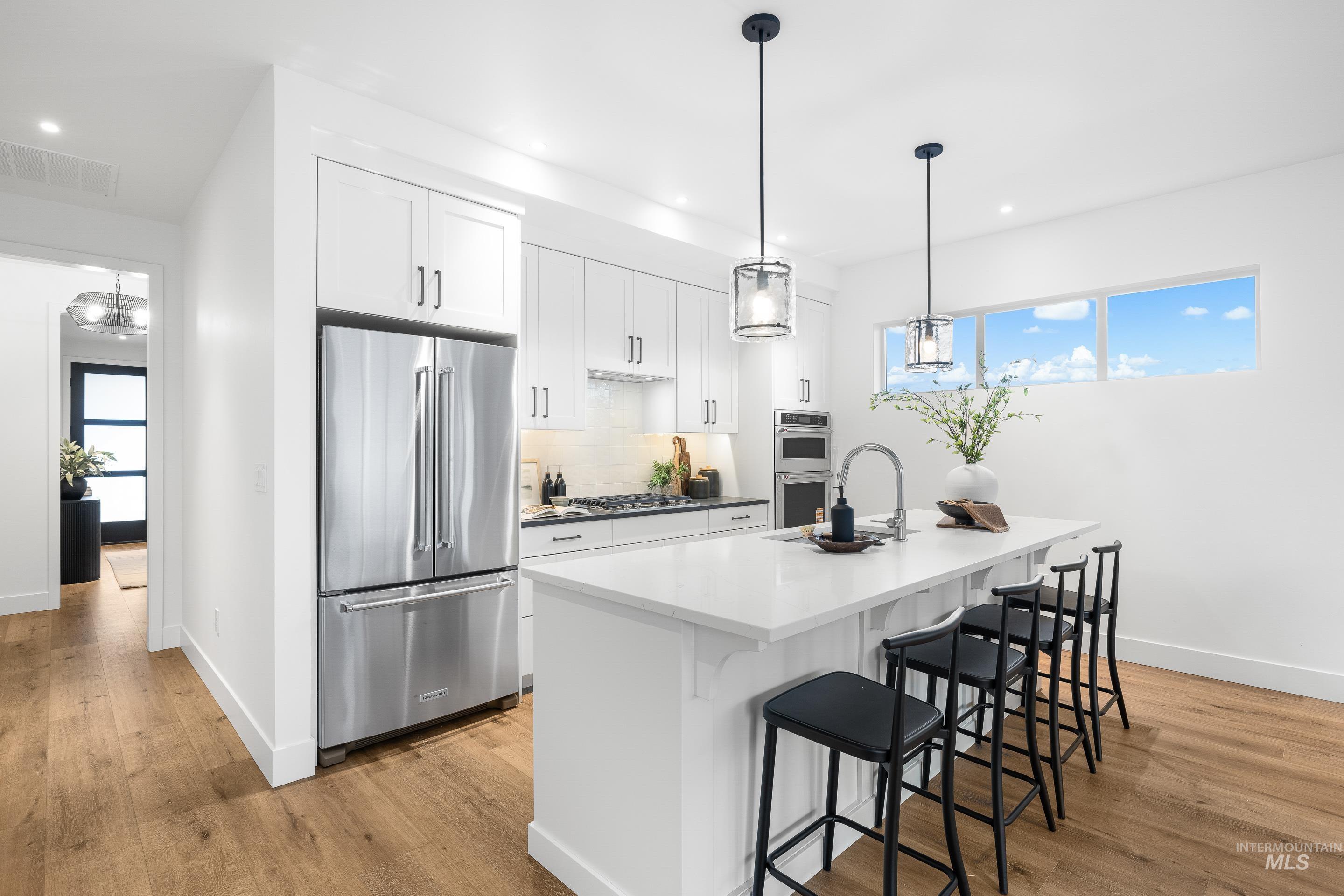 3071 North Lapis Avenue Meridian, ID 83646 - Photo 9 of 50 Kitchen with white cabinets, appliances with stainless steel finishes, a kitchen bar, light wood-style floors, and recessed lighting