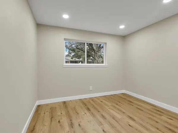 an empty room with wooden floor and windows
