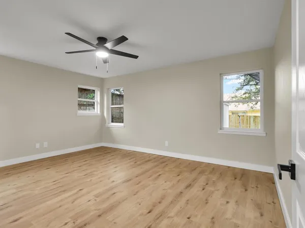 a view of an empty room with wooden floor and a window
