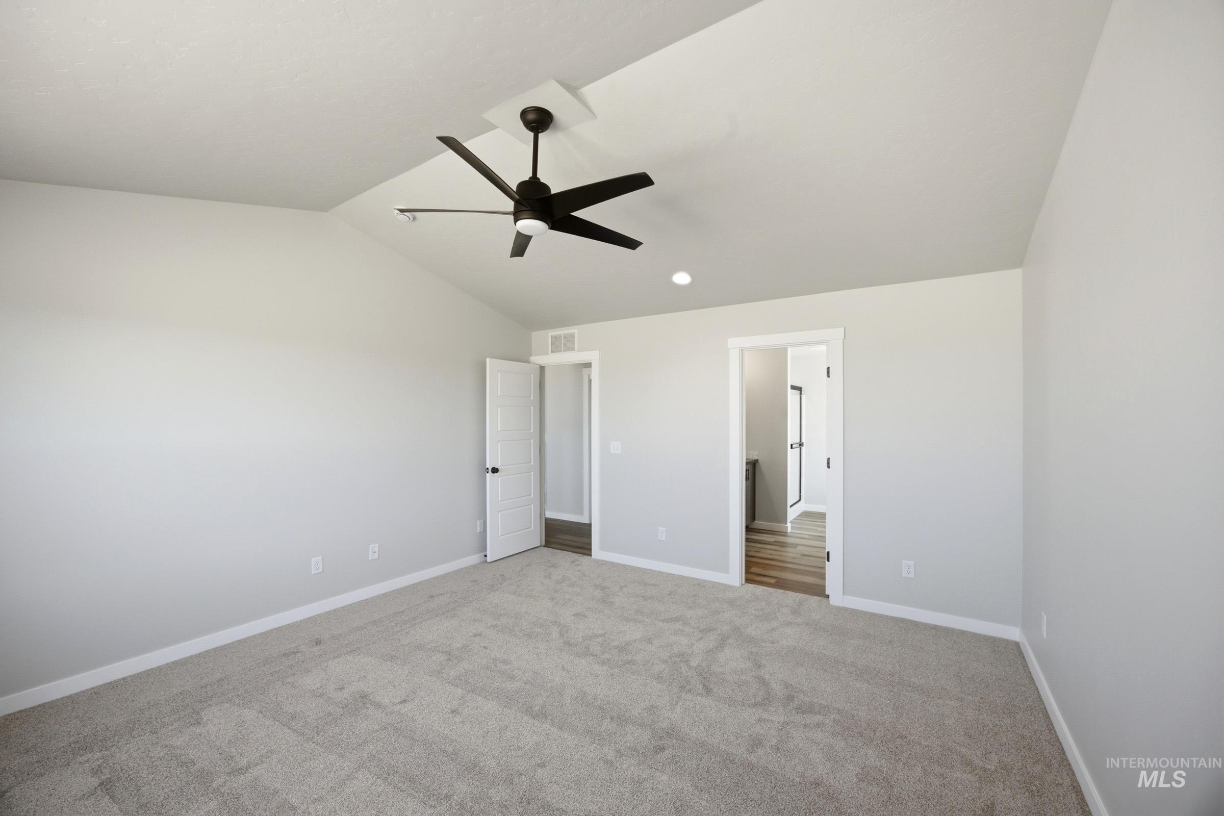 4344 East Rincon Drive Meridian, ID 83642 - Photo 22 of 26 Spacious primary bedroom featuring vaulted ceilings, a contemporary ceiling fan with integrated lighting, neutral carpet flooring, and dual closet access