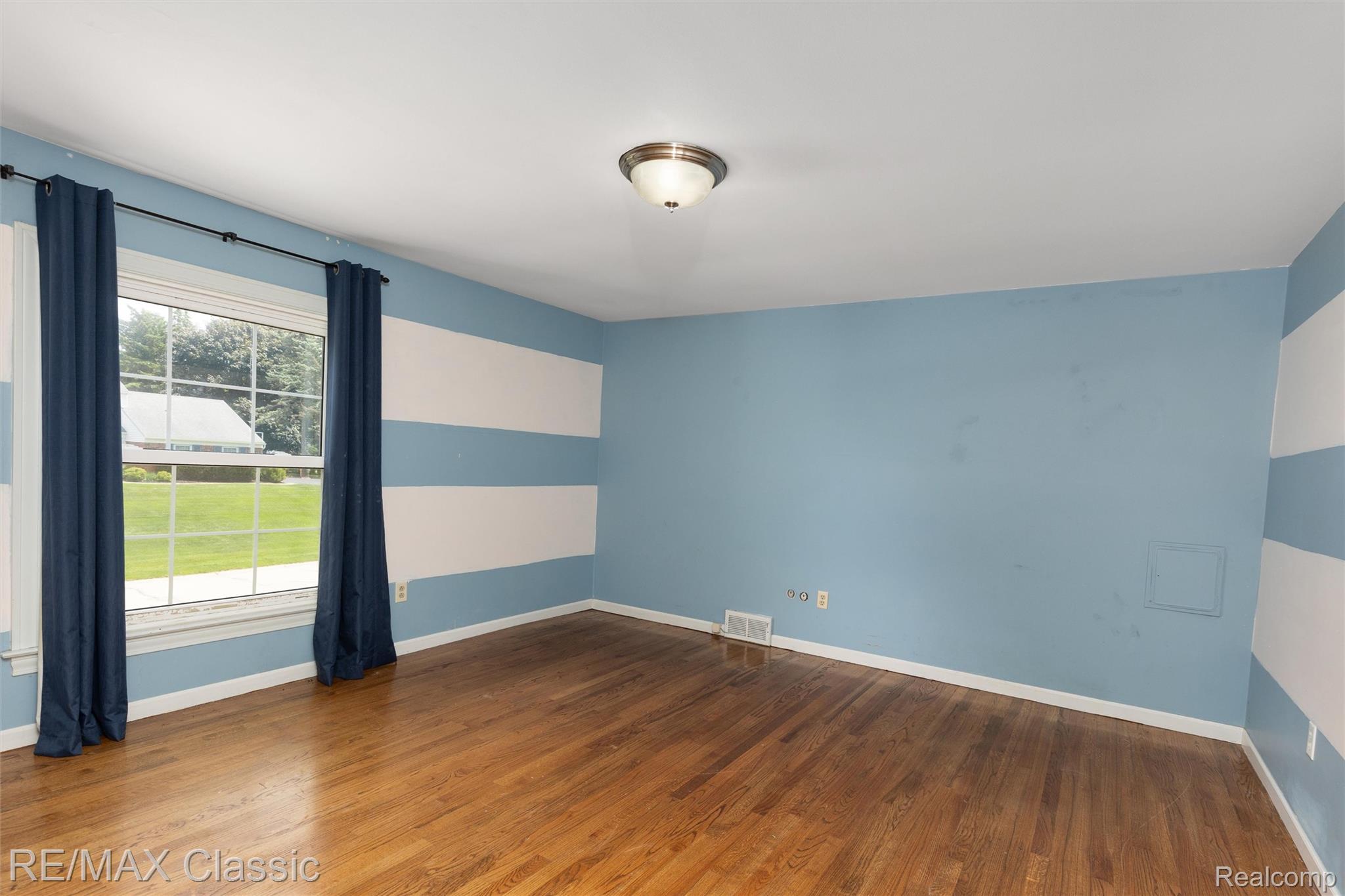 4268 Covered Bridge Road Bloomfield Hills, MI 48302 - Photo 18 of 35 Bedroom featuring hardwood flooring, a large window, a flush mount ceiling light, and striped accent walls