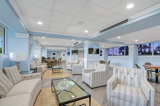 a view of a dining room and livingroom with furniture wooden floor a rug a painting and a chandelier