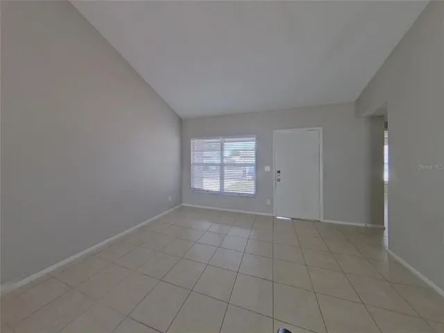 a view of an empty room with window and chandelier fan