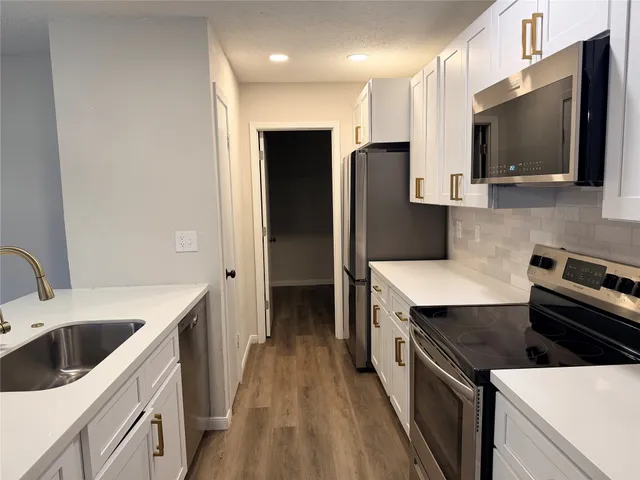 a kitchen with a sink a counter top space stainless steel appliances and cabinets