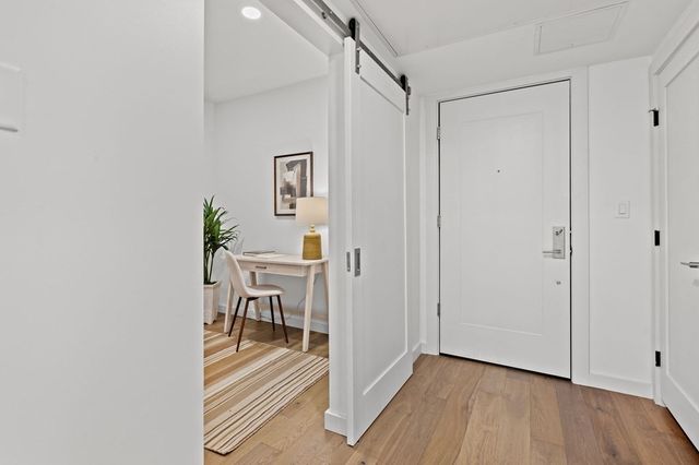 a view of a hallway with wooden floor and a bathroom
