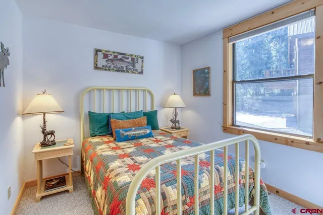 a bedroom with a bed and a lamp on the dresser