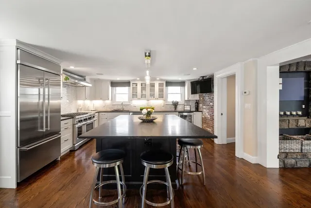 a kitchen with stainless steel appliances granite countertop a dining table chairs refrigerator and sink
