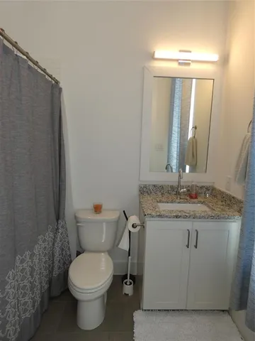 a bathroom with a granite countertop toilet sink and mirror