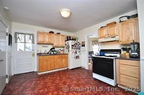 a kitchen with stainless steel appliances granite countertop a stove a refrigerator and a sink with wooden cabinets