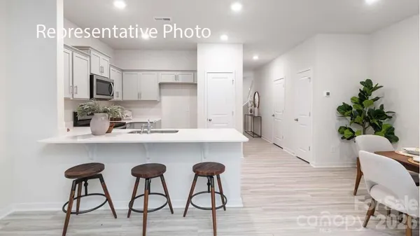 a kitchen with stainless steel appliances a dining table chairs refrigerator and cabinets