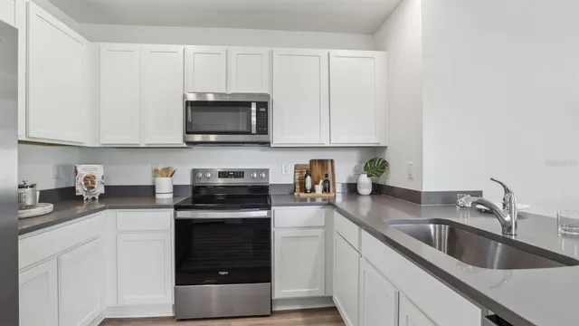 a kitchen with granite countertop white cabinets and stainless steel appliances