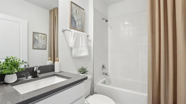 a bathroom with a granite countertop sink a toilet and shower