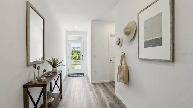 a view of a hallway with wooden floor and a bathroom