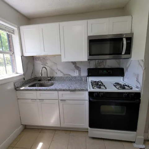 a kitchen with granite countertop a stove and a microwave