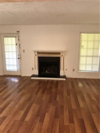 an empty room with wooden floor a fireplace and windows