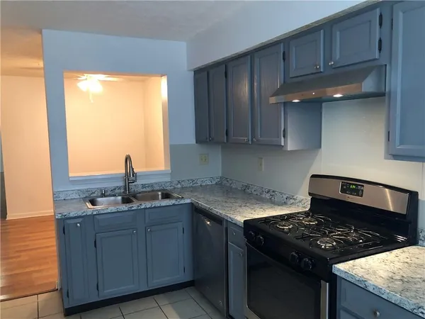 a kitchen with granite countertop stainless steel appliances a sink stove and cabinets