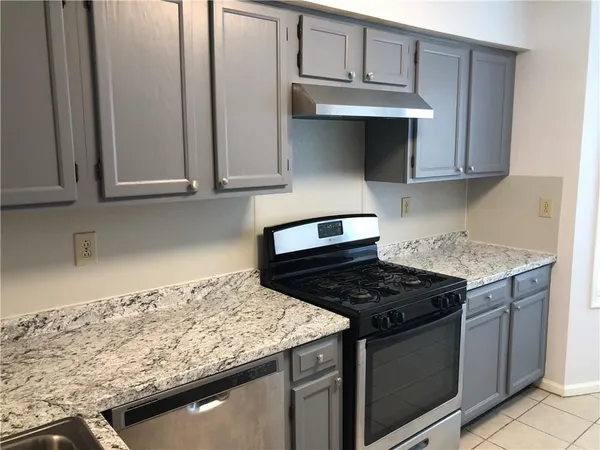 a kitchen with granite countertop stainless steel appliances a stove a sink and cabinets