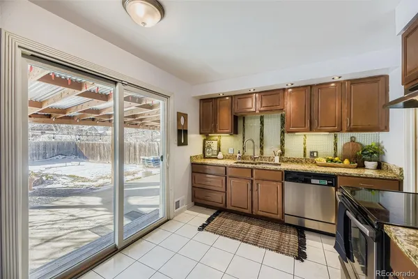 a kitchen with stainless steel appliances granite countertop a stove top oven a sink dishwasher a dining table and chairs with wooden floor