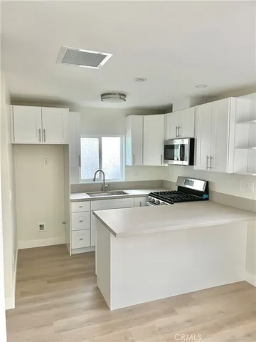 a kitchen with stainless steel appliances granite countertop a stove a sink and white cabinets
