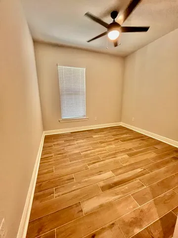 a view of an empty room with window and chandelier fan