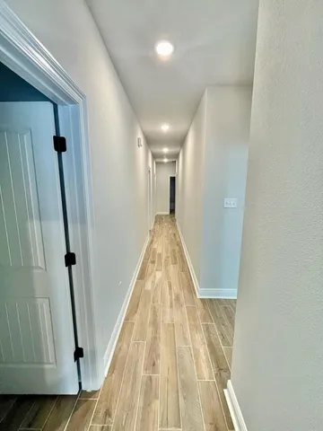 a view of a hallway with wooden floor and staircase