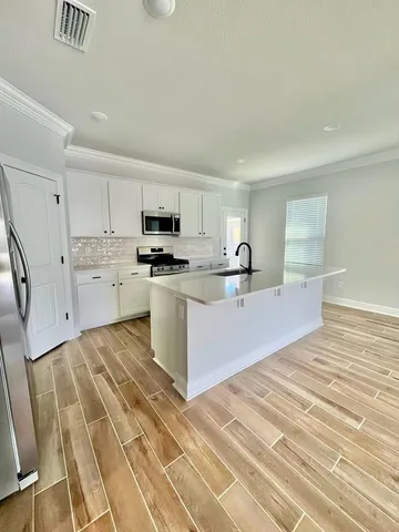 a large white kitchen with kitchen island sink stainless steel appliances and cabinets