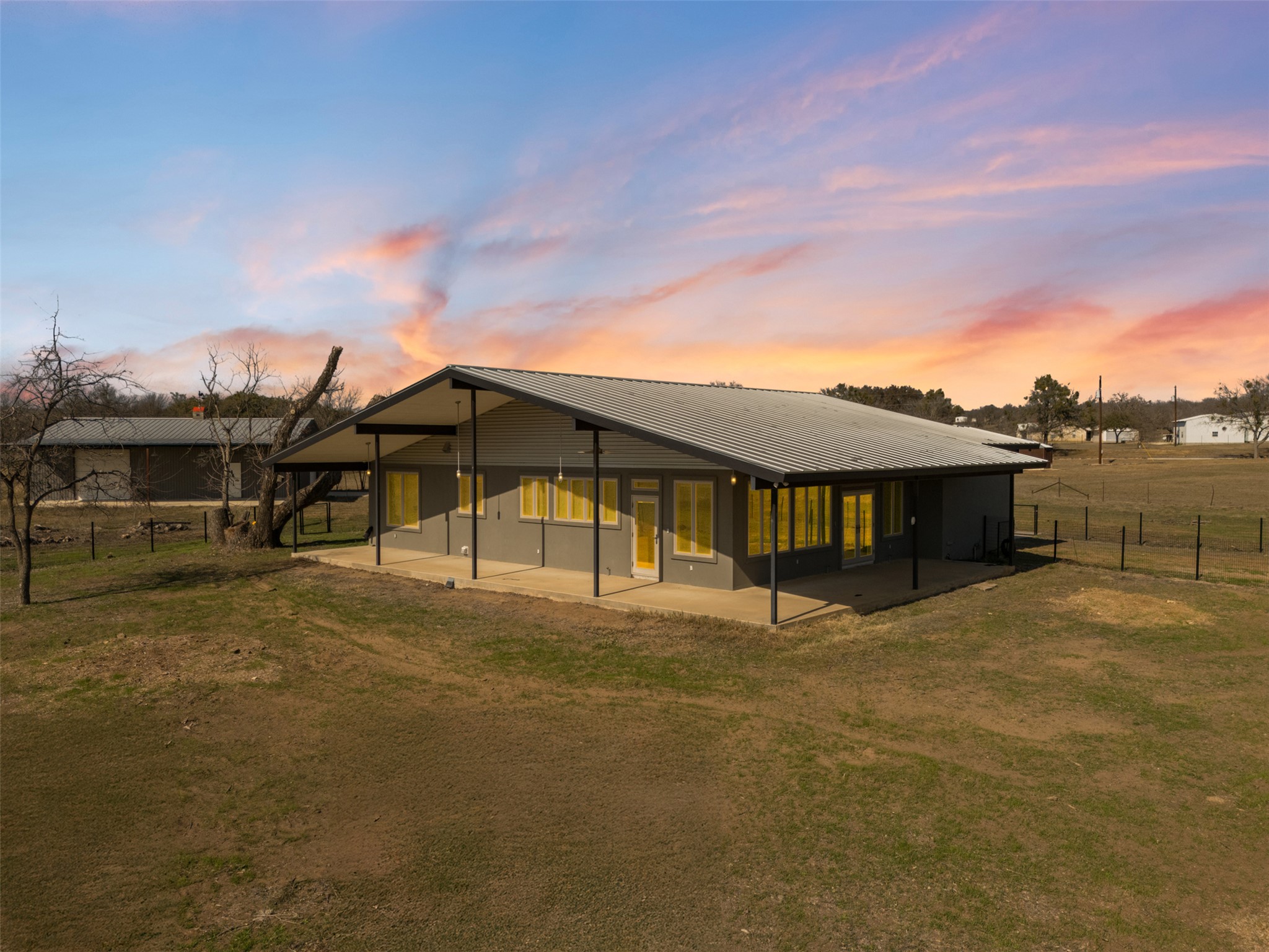 1150 Timber Ridge Road Marble Falls, TX 78654 - Photo 1 of 1 Back of property at dusk with a lawn, metal roof, fence, and a patio area