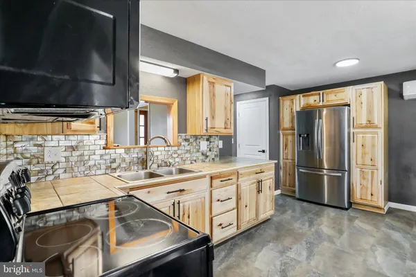 a kitchen with stainless steel appliances kitchen island granite countertop a refrigerator and a stove top oven