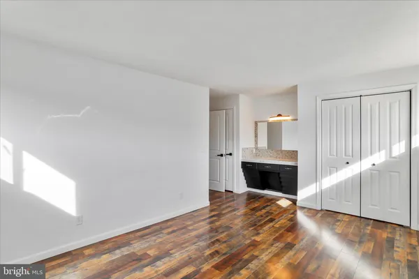 a view of an empty room with wooden floor fireplace and a window