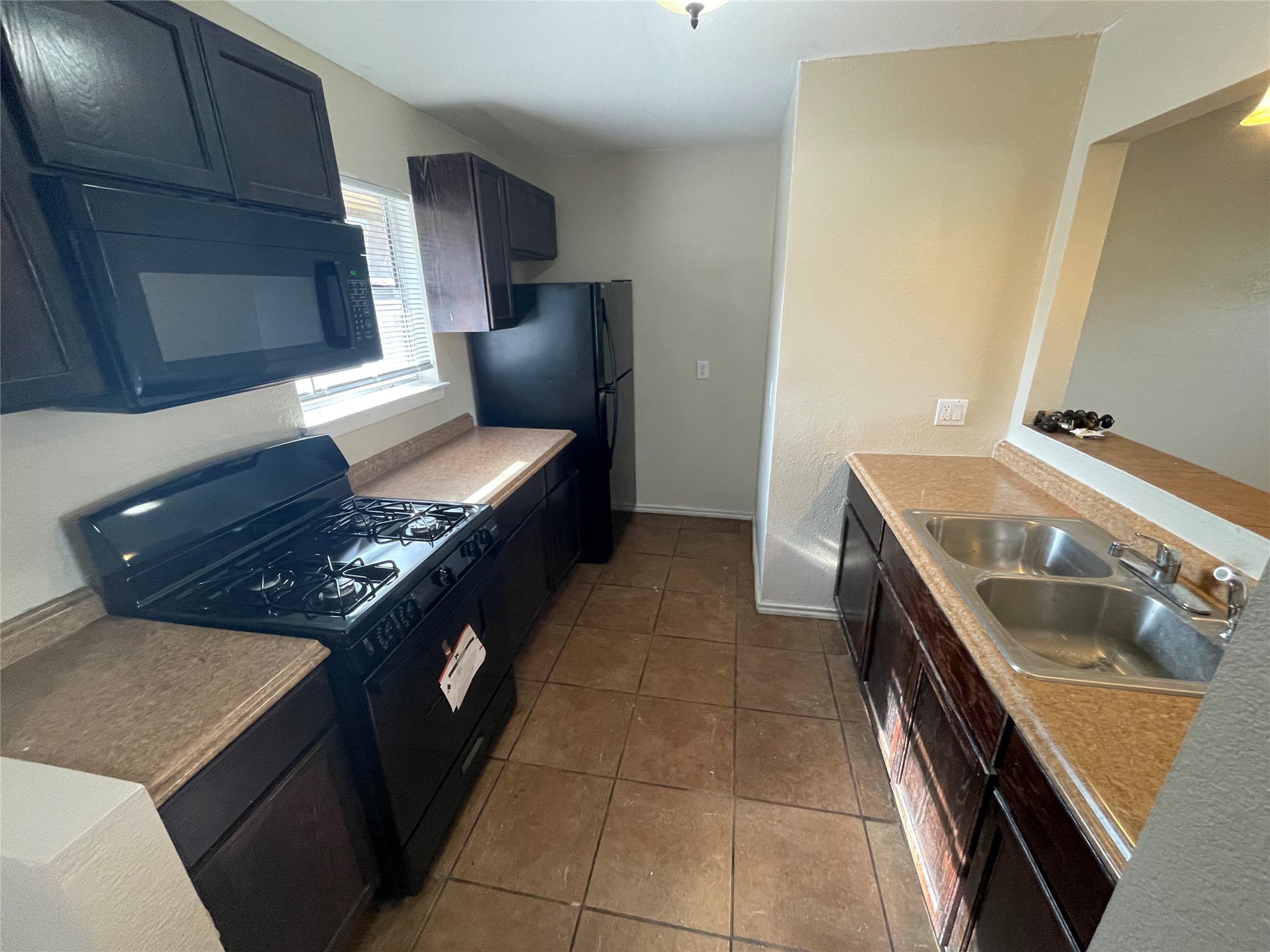 6253 Manor Road, Unit B Austin, TX 78723 - Photo 2 of 10 Kitchen with black appliances, dark tile patterned floors, light countertops.