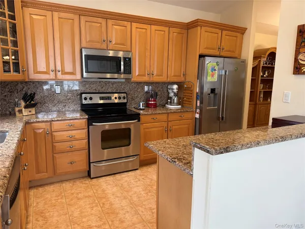 a kitchen with stainless steel appliances kitchen island granite countertop a refrigerator and microwave