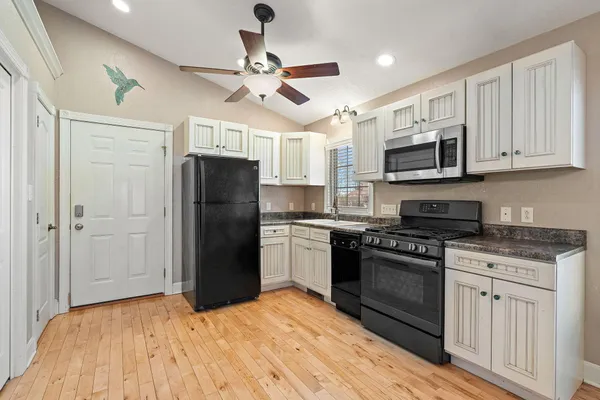 a kitchen with stainless steel appliances granite countertop a refrigerator a sink a stove and white cabinets