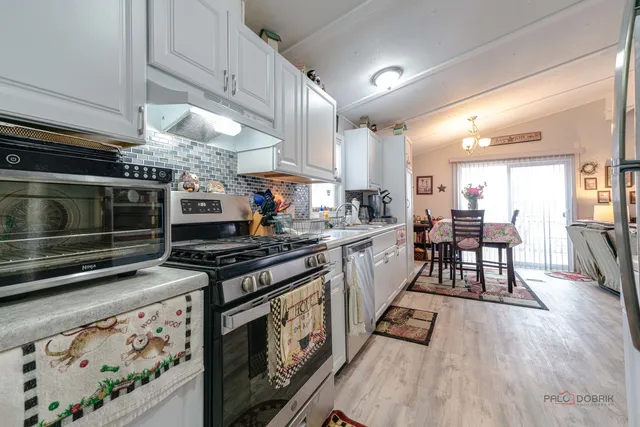 a kitchen with stainless steel appliances a stove a sink dishwasher and cabinets with wooden floor