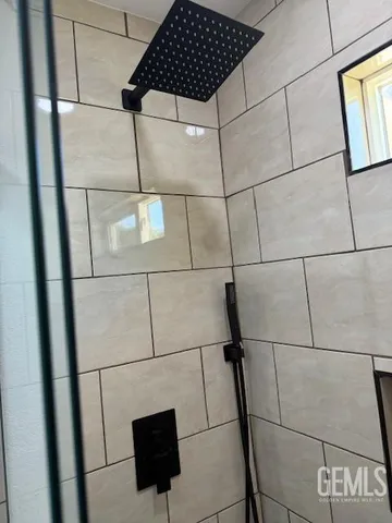 a bathroom with a shower and a tiled wall