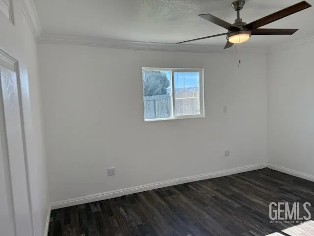 an empty room with wooden floor ceiling fan and windows
