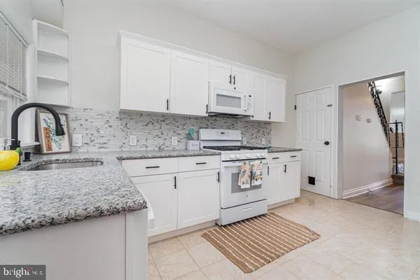 a kitchen with granite countertop white cabinets and white appliances