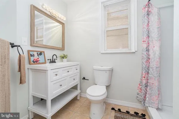 a bathroom with a sink toilet a mirror and shower curtain