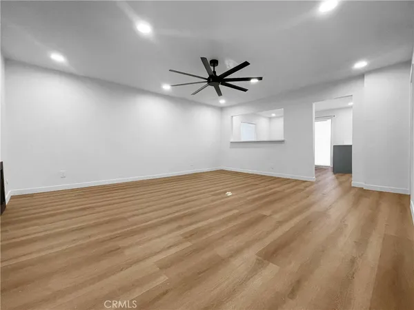 an empty room with wooden floor ceiling fan and windows