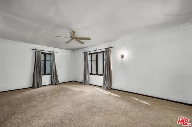 an empty room with chandelier fan and windows