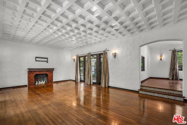 a view of an empty room with wooden floor and a fireplace