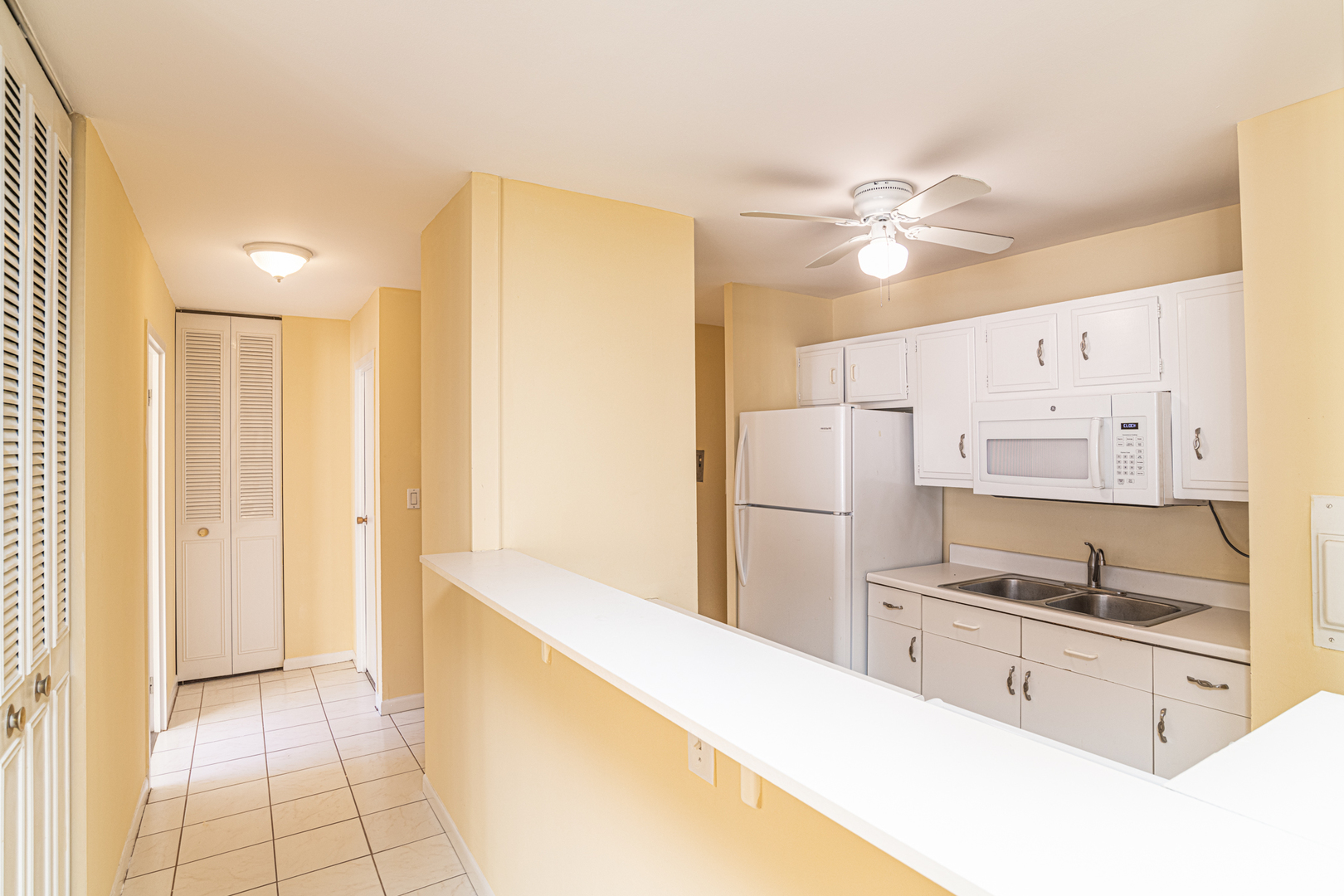 6171 North Sheridan Road, Unit 2404 Chicago, IL 60660 - Photo 5 of 16 a kitchen with granite countertop a refrigerator a sink and white cabinets