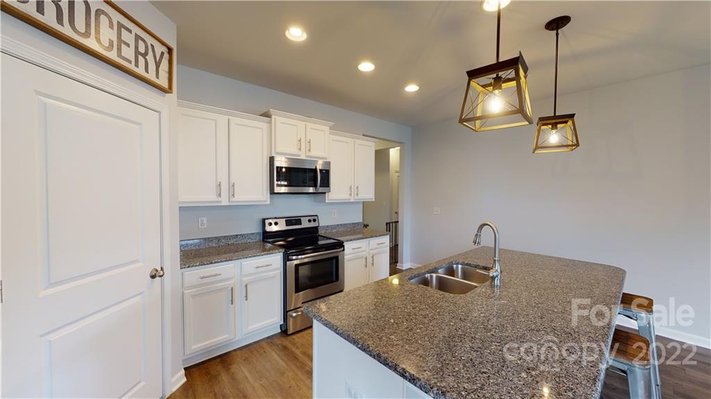 408 Accord Street Myrtle Beach, SC 29588 - Photo 12 of 43 a kitchen with stainless steel appliances granite countertop a sink dishwasher a stove top oven a dining table and chairs with wooden floor