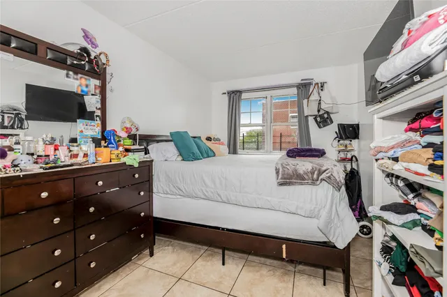 a bedroom with a bed a flat screen tv and a window