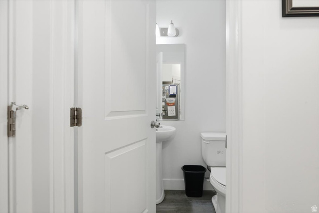1213 West 1820th Street South Logan, UT 84321 - Photo 8 of 18 Powder room featuring a pedestal sink, white toilet, wall-mounted mirror, and overhead vanity lighting