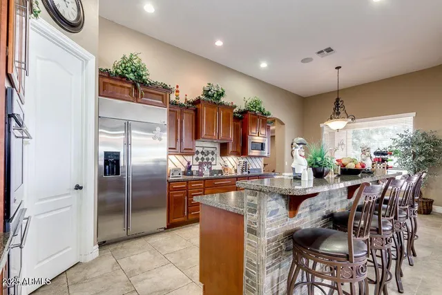 a kitchen with stainless steel appliances kitchen island granite countertop a refrigerator and a stove top oven