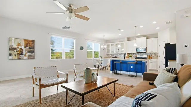 a living room with furniture kitchen view and a chandelier