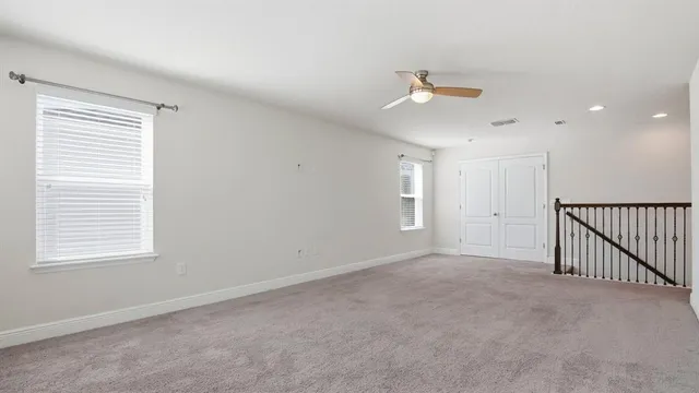 an empty room with chandelier fan and windows