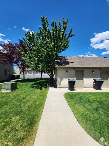 2525 West 450 South, Unit 8 Springville, UT 84663 - Photo 20 of 22 Manicured lawn with a concrete pathway leading to a building featuring horizontal siding, exterior lighting fixtures, and a shingled roof
