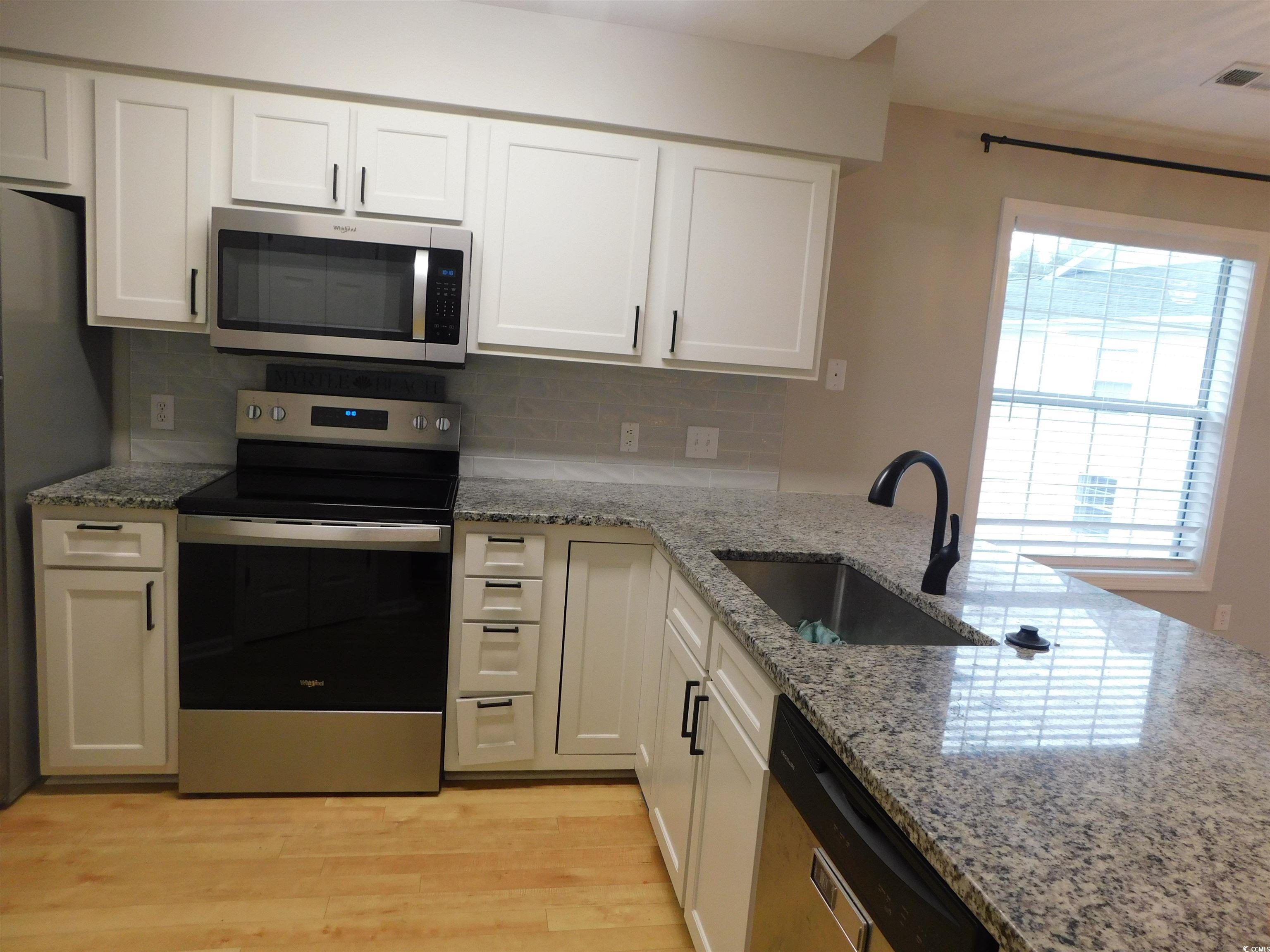 517 White River Drive, Unit BUILDING 22 G Myrtle Beach, SC 29579 - Photo 4 of 17 Kitchen with stainless steel dishwasher, dark stone counters, light wood-type flooring, ceiling fan, and pendant lighting